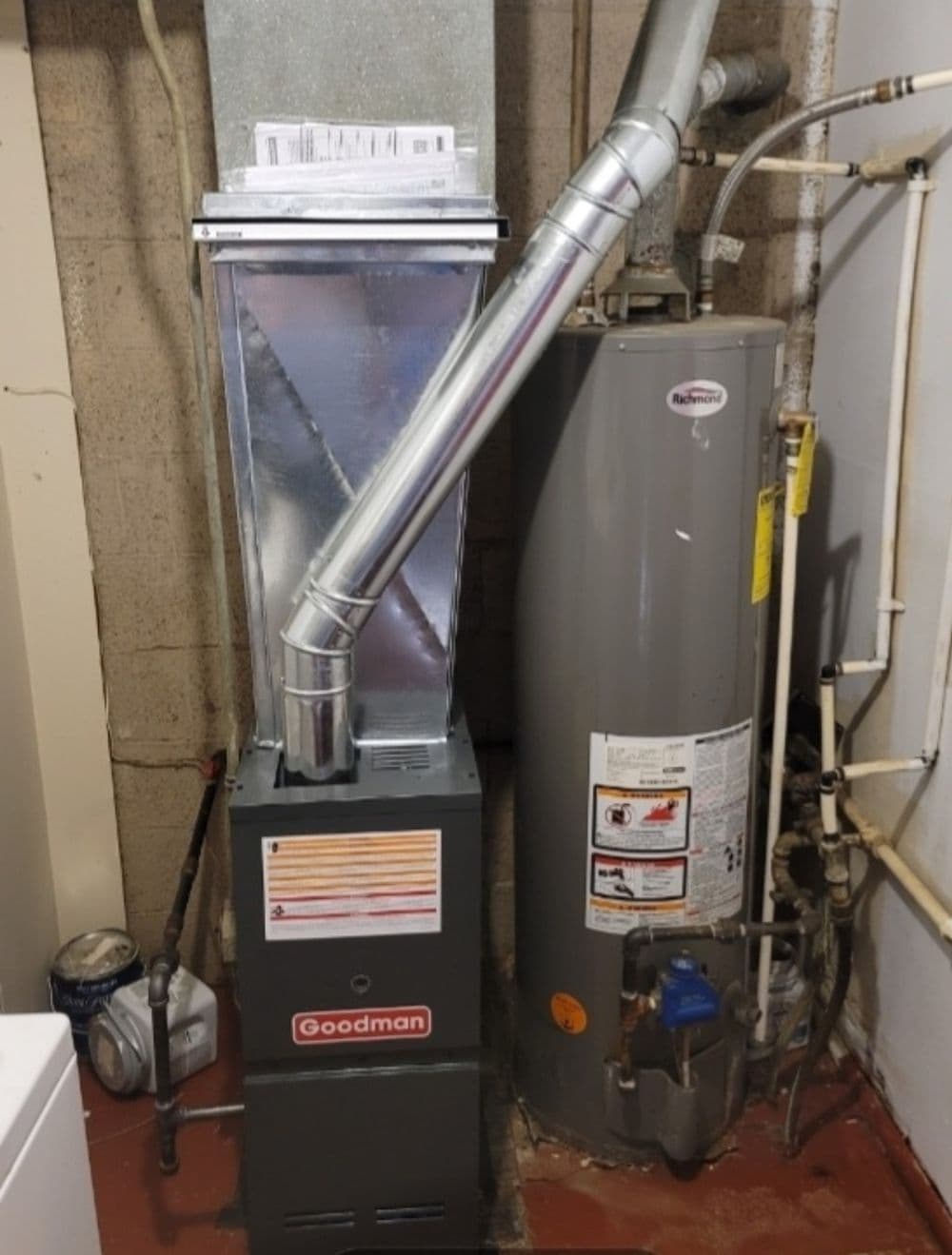 Goodman gas furnace and water heater in a residential basement setting.
