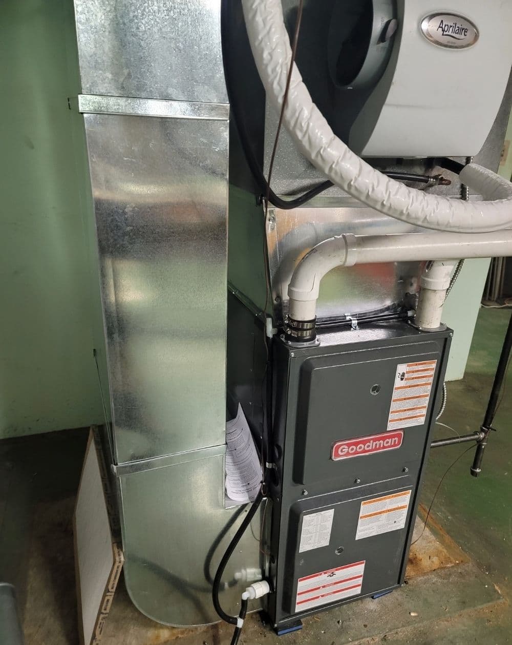 Goodman HVAC furnace installation with metal ductwork and Aprilaire filter system.