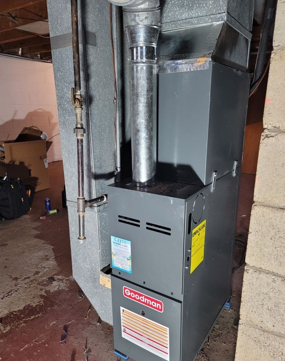 Goodman furnace with metal ductwork in a basement setting, ideal for home heating solutions.